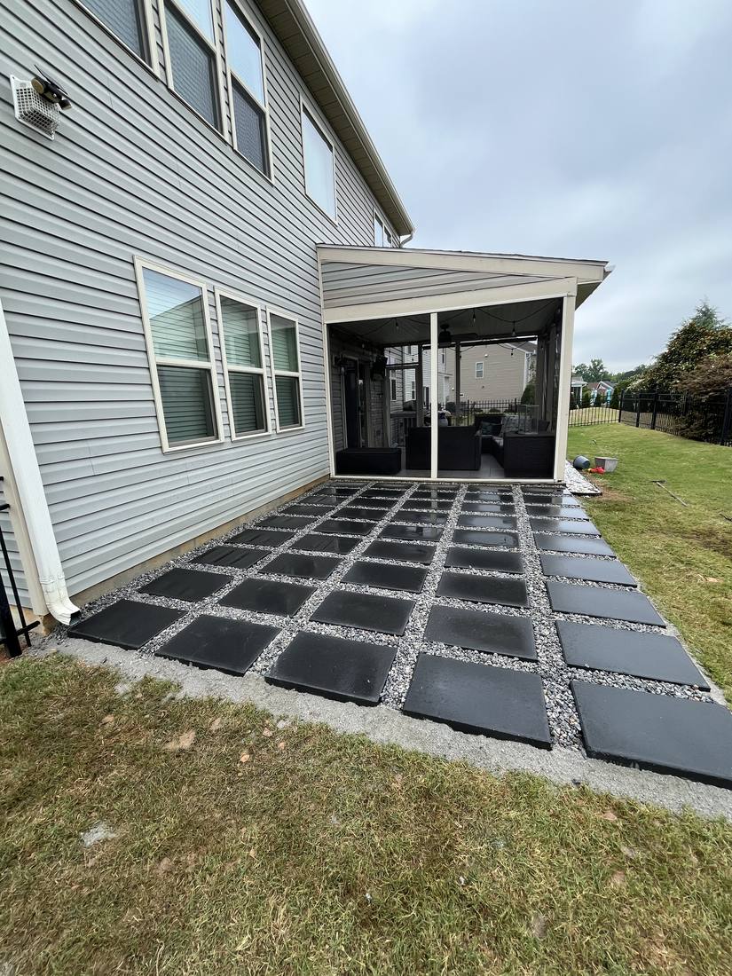Finished paver grid patio with gravel joints beside the same screened porch
